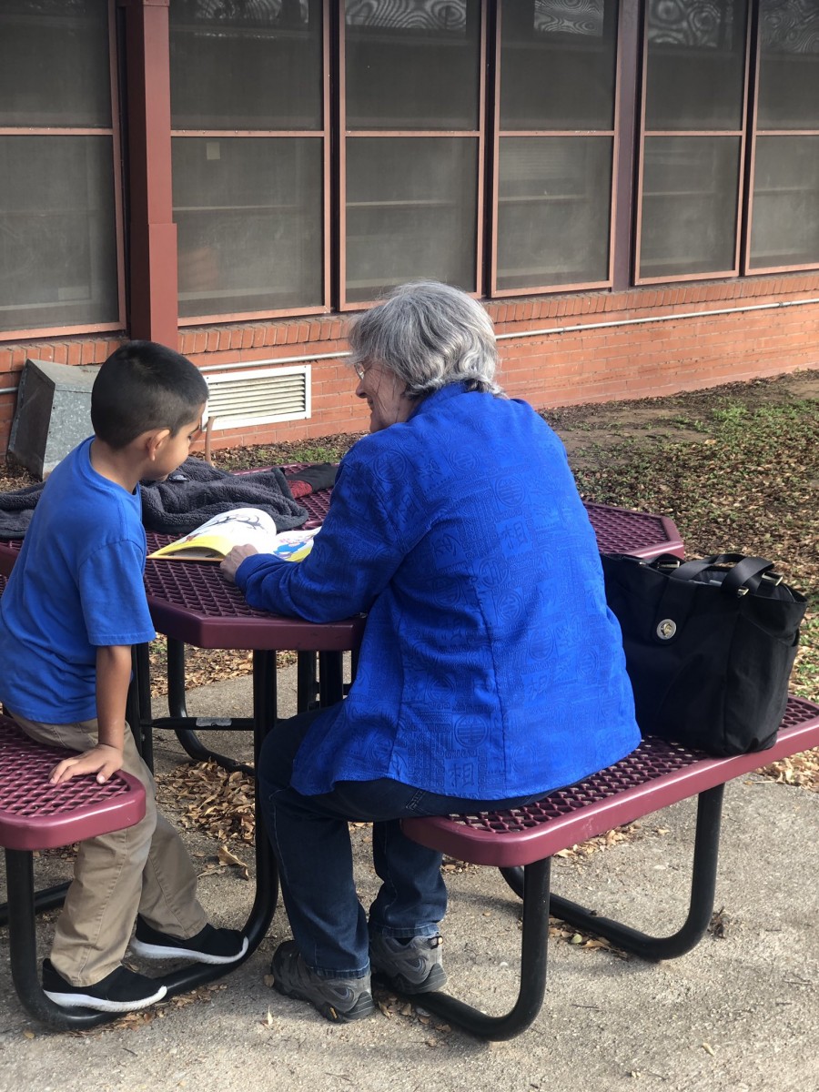 Reading Buddy volunteer reading with a student